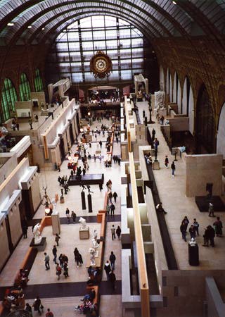 People on the museum floor below, giant clock on distant wall