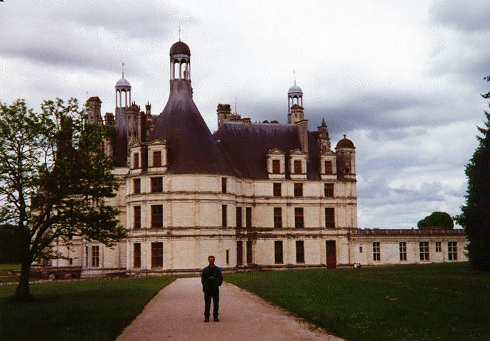 Some guy standing in front of a big chateau