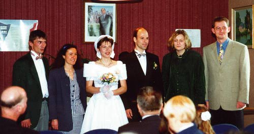 Six people, the middle two in wedding garb